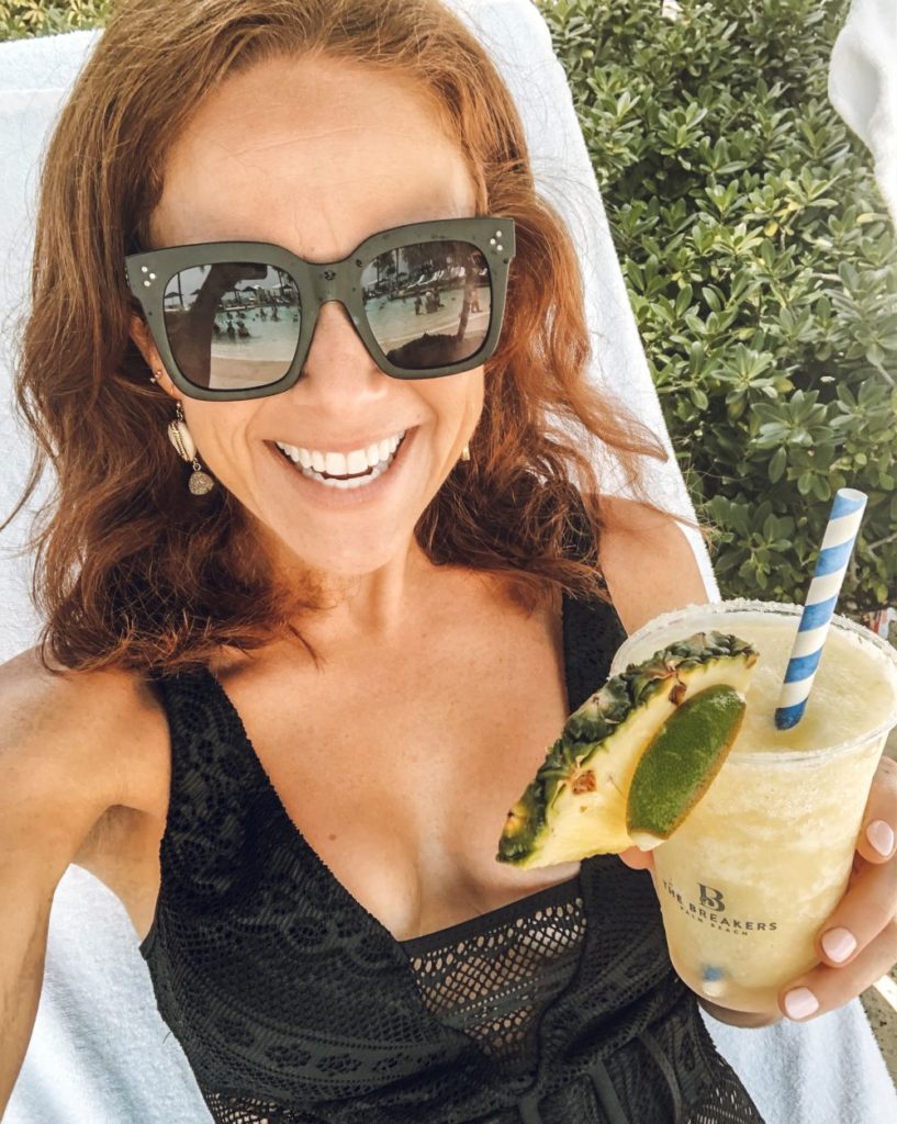 Alyson's Recent Favorites // July 2019 by popular Florida lifestyle blog: The Modern Savvy: image of a woman lounging in a pool chair, holding a cocktail and wearing a pair of Celine sunglasses.