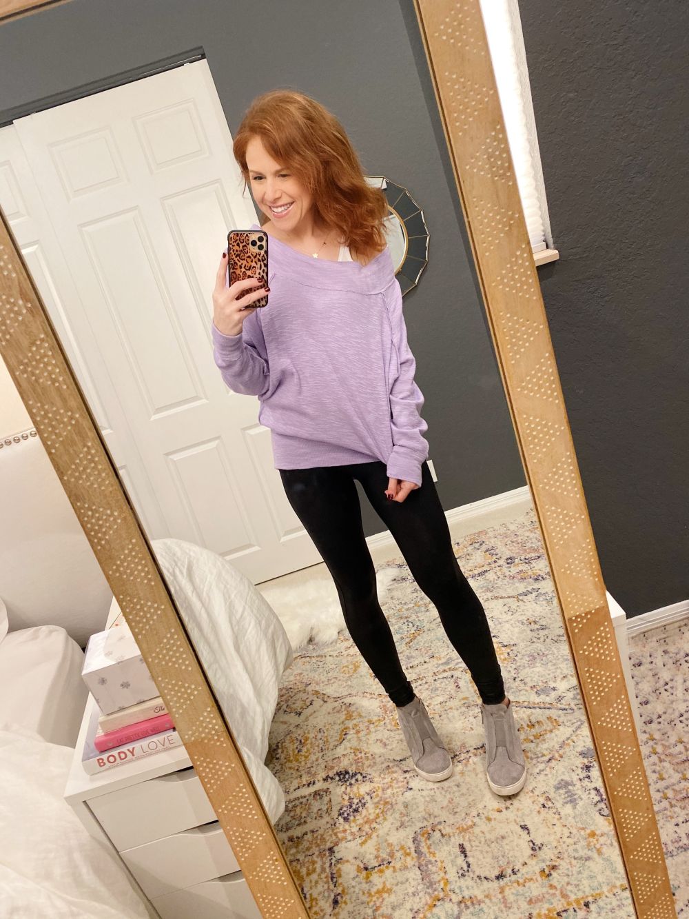 How to Style Spanx Leggings by popular Florida fashion blog, The Modern Savvy: image of a woman wearing Nordstrom Faux Leather Leggings SPANX®, purple tunic, Nordstrom Felicia Wedge Bootie and holding a phone in a Amazon Sonix Watercolor Leopard Case for iPhone 11 Pro.