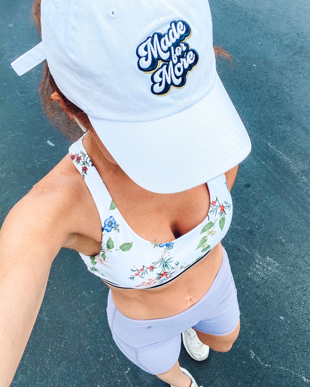 Home Workout Equipment Ideas by popular Florida lifestyle blog, The Modern Savvy: image of a woman wearing a white ball cap, floral bralette, white sneakers, and purple bike shorts. 