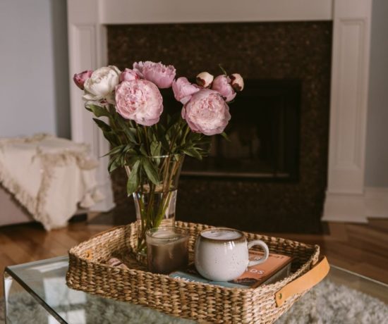 Favorite Weekend Sale by popular Florida life and style blog, The Modern Savvy: image of a vase of peonies in a wicker nesting basket on a glass coffee table.