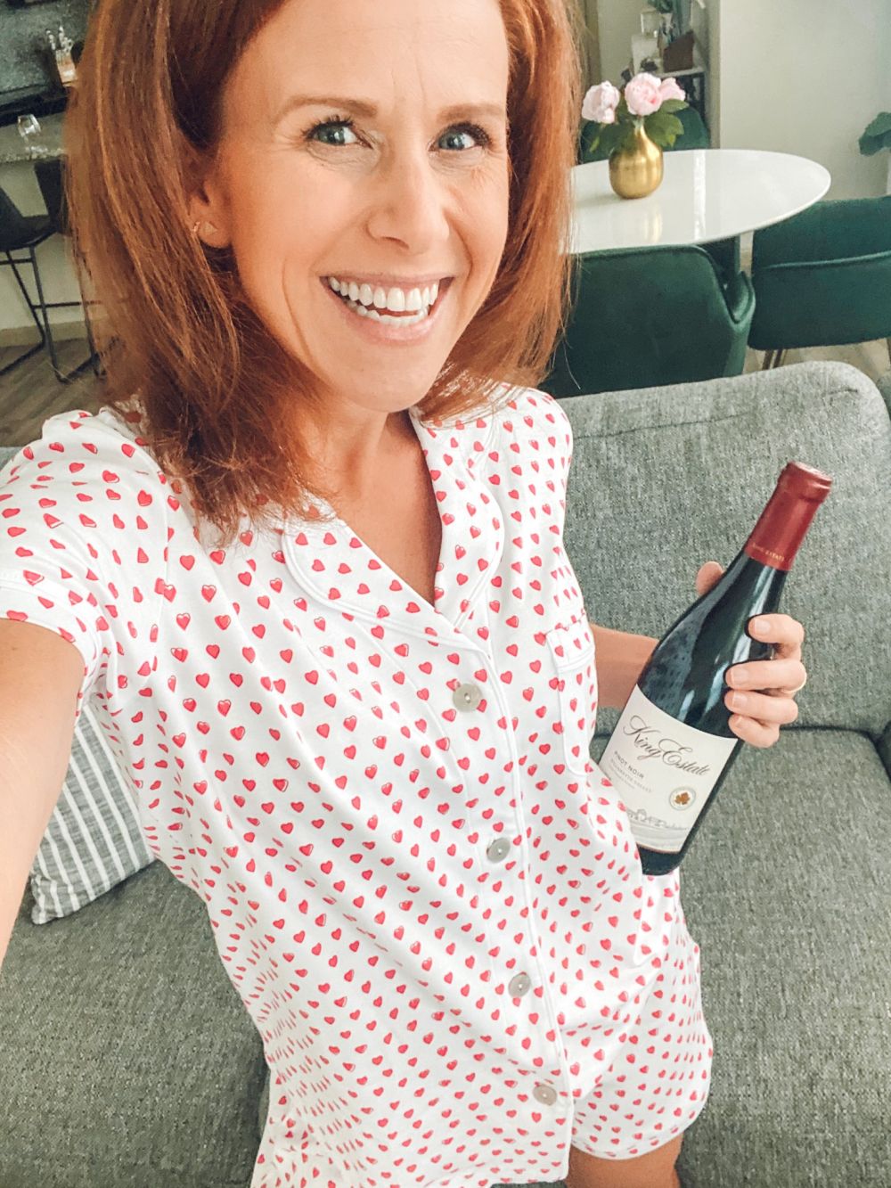 How to Feel Happy Again by popular Florida lifestyle blog, The Modern Savvy: image of a woman wearing Roberta Roller Rabbit heart print pajamas and holding a bottle of red wine. 