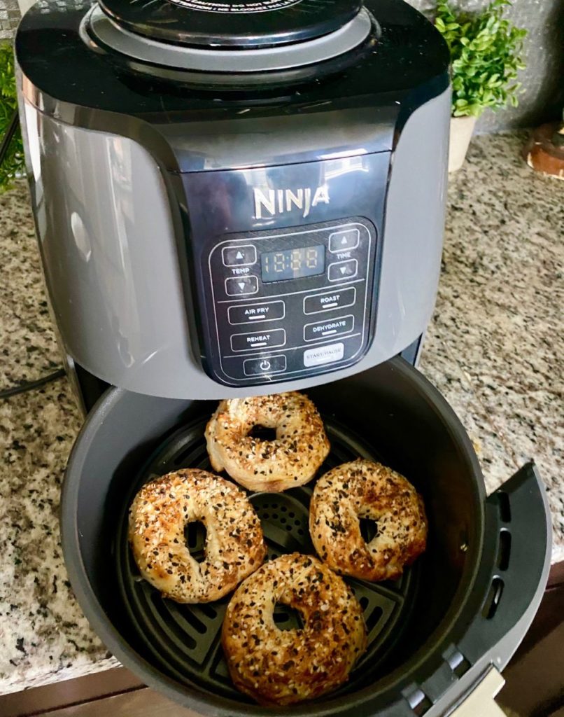 Bagel Recipe by popular Florida lifestyle blog, The Modern Savvy: image of some bagels in a Ninja air fryer. 