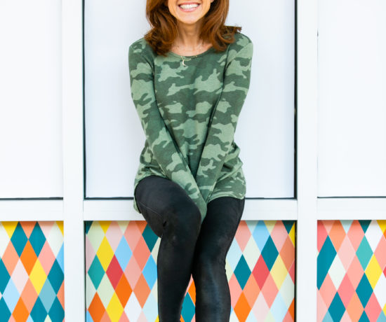 Cyber Week Deals by popular Florida life and style blog, The Modern Savvy: image of a woman wearing a long sleeve camo shirt and black leather leggings with a pair of white sneakers.